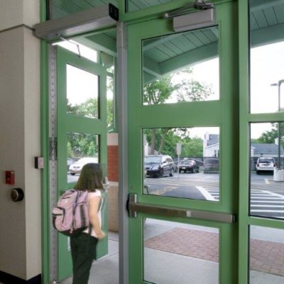 This Is A Photo Of A Child Leaving A School Via A Door With Panic Bars And Door Openers And Closers Installed.